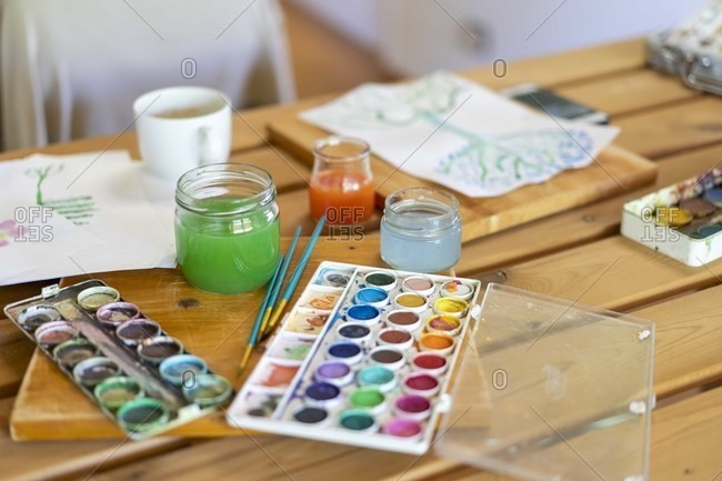 Watercolor paints with water and paintbrushes on wooden table home