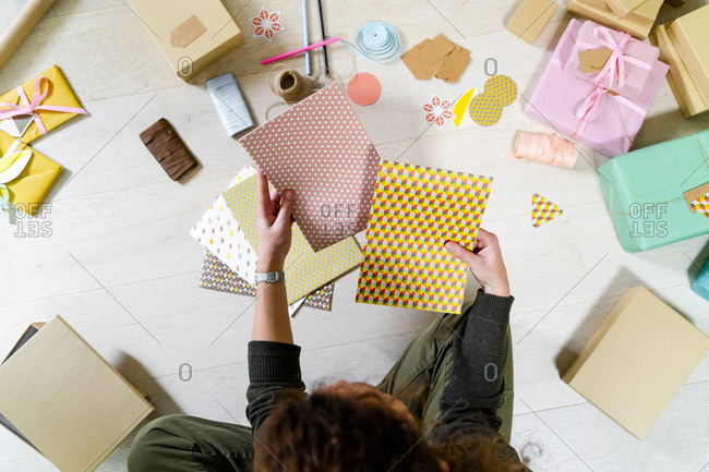 Young woman sitting on the floor at home wrapping gift