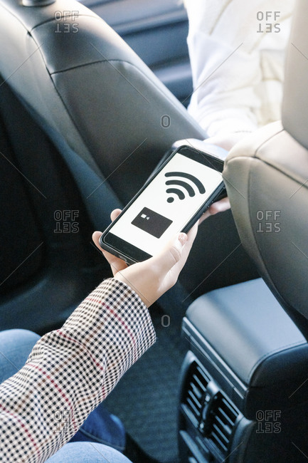 Cropped hand of woman making mobile payment in taxi