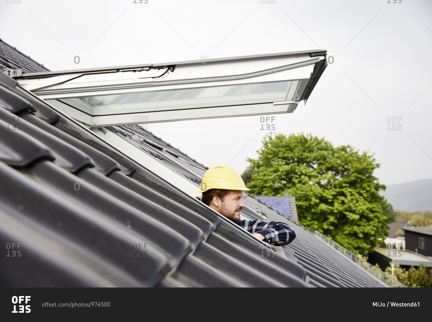 Man wearing hard hat looking out of roof window