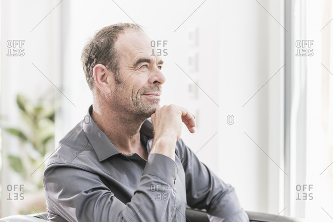 Portrait of pensive businessman sitting in armchair looking at distance
