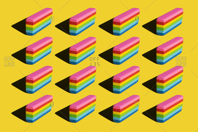 Pattern of rainbow colored erasers against yellow background