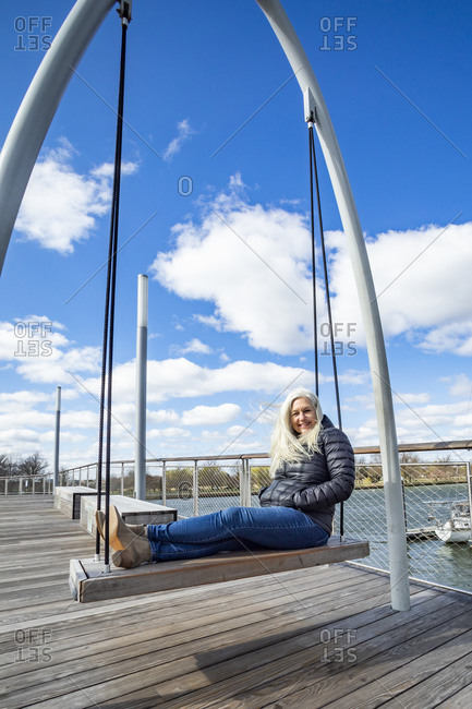 USA, Washington D.C., Senior woman on swing at Wharf District along Potomac River