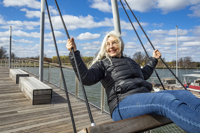 USA, Washington D.C., Senior woman on swing at Wharf District along Potomac River