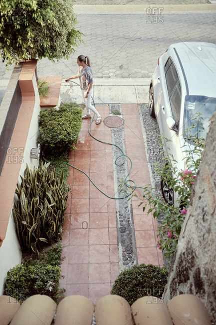 Mexico, Zapopan, Woman watering plants in driveway