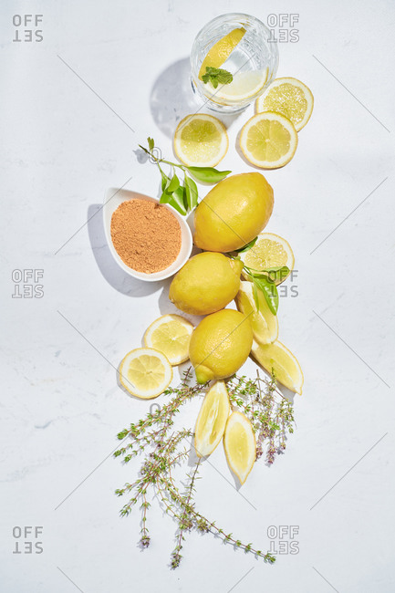 Top view set of various ingredients for recipe of healthy refreshing ginger and thyme lemonade arranged on white marble table
