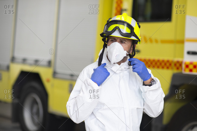 Serious fireman in protective costume and wearing respirator on fire station during coronavirus pandemic