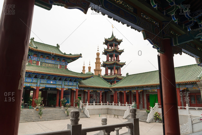 Exterior of oriental building with curved roof and ornamental pagodas on background of cloudless sky
