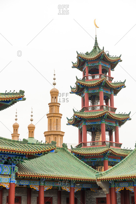 Exterior of oriental building with curved roof and ornamental pagodas on background of cloudless sky