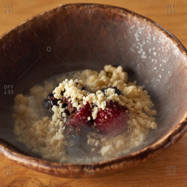 Berry frozen crumble with raspberries, blackberries and blue berries in a small bowl with a bit of chocolate