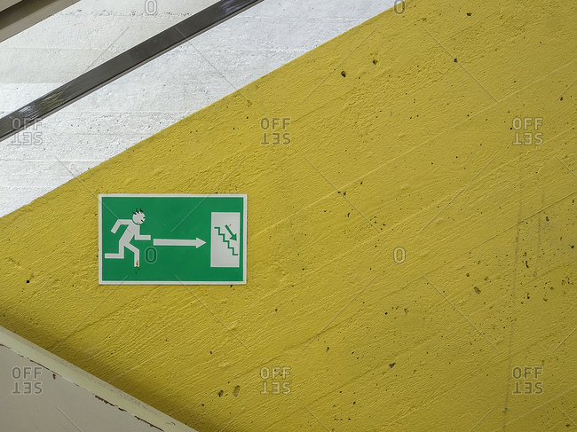 Green emergency exit sign against yellow