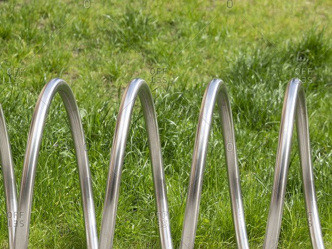Abstract metal bicycle stand against green grass