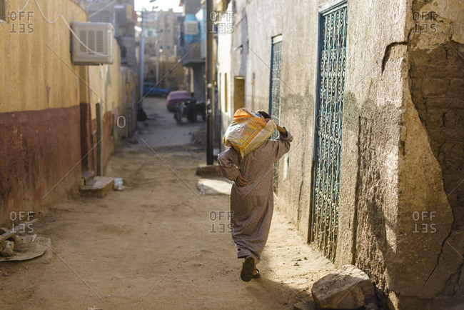 Young man with heavy sack on the streets of Aswan, Egypt