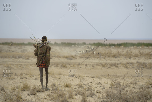 August 2, 2014: A Turkana warrior walks through the desert to protect his herd of goats, Kenya