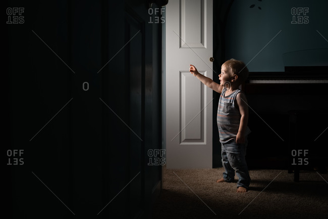 Toddler boy looking into lit doorway in awe