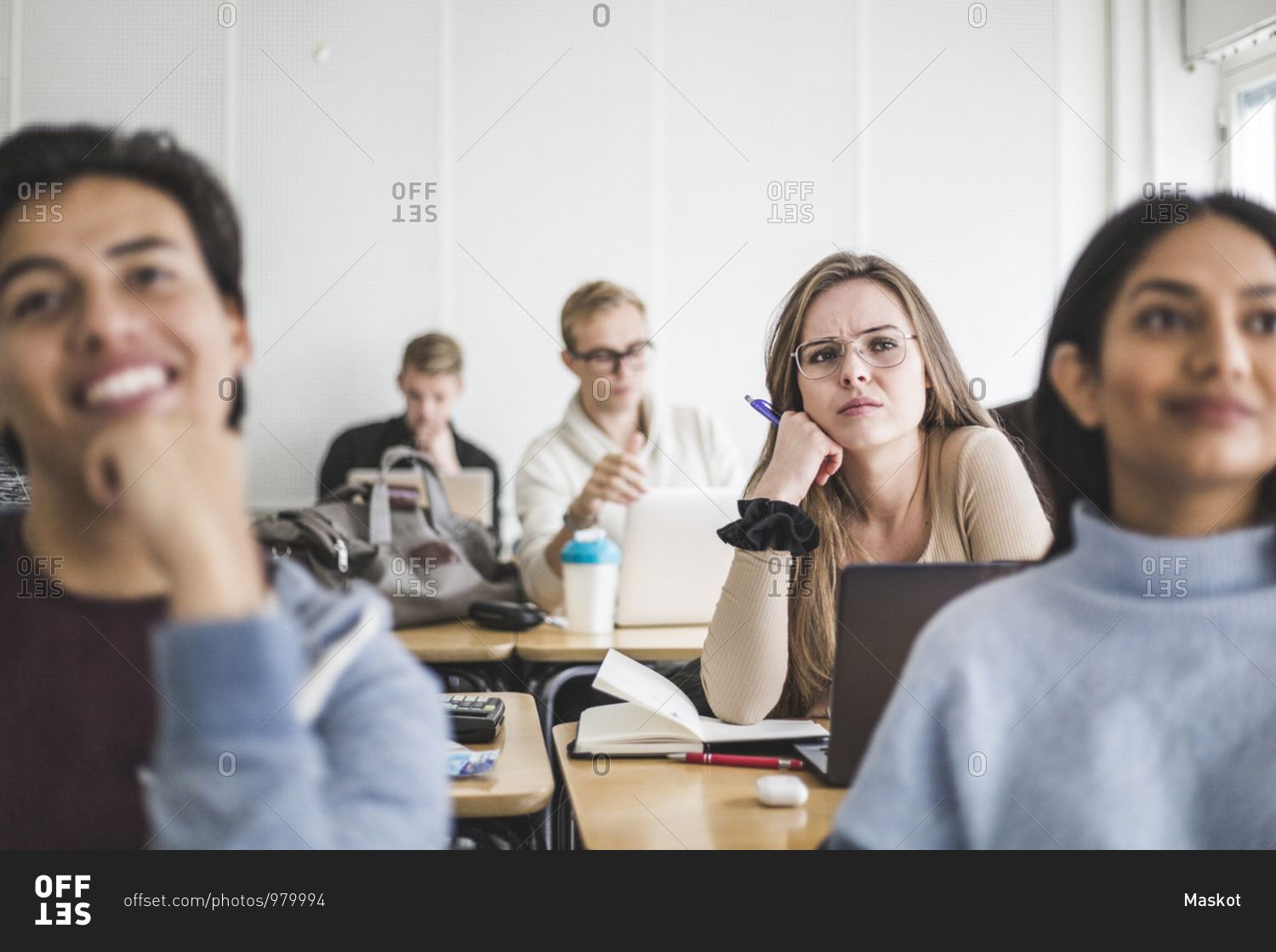 Young woman with friends listening while sitting in classroom