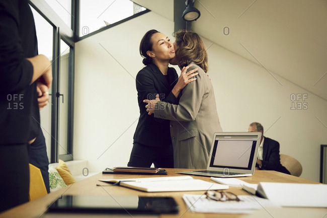 Female lawyers embracing while greeting in office during meeting