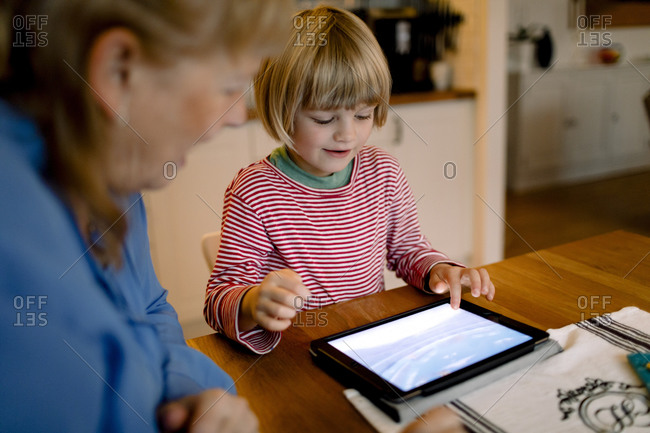 Grandmother looking at grandson using digital tablet