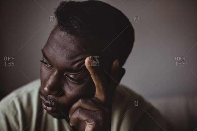 Close-up of sad man holding head in hand while looking away