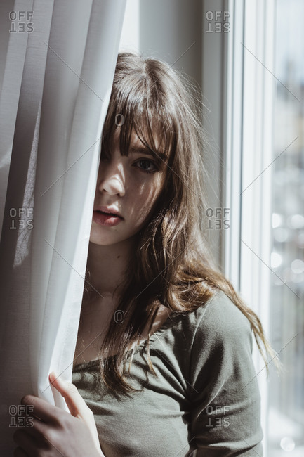 Portrait of woman standing by curtain
