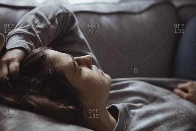 Close-up of sad woman lying on sofa at home