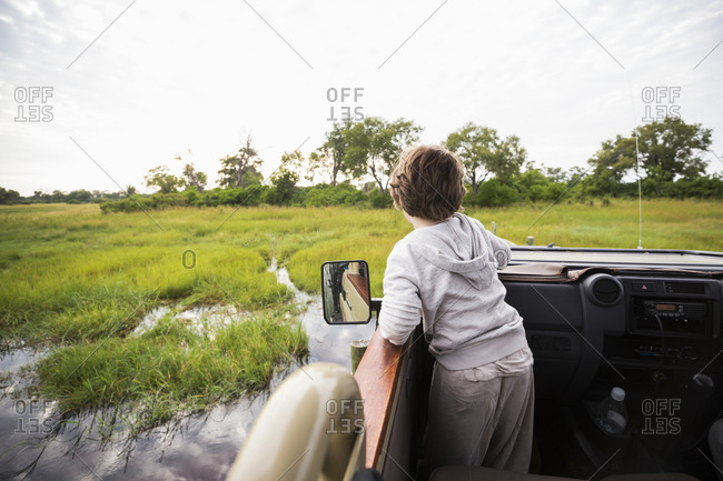 A six year old boy in a safari jeep driving through water in marshes.