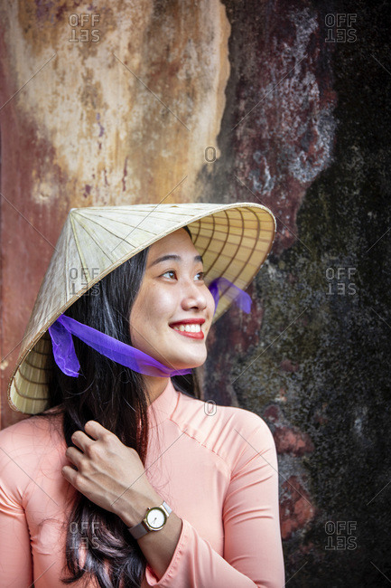 January 9, 2019: A young Vietnamese woman in a traditional Ao Dai dress and conical hat and smiling, Hue, Vietnam, Indochina, Southeast Asia, Asia