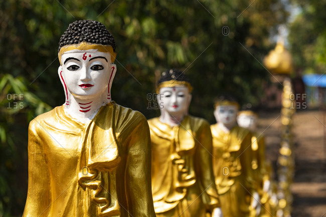 Long line of golden Buddhas lining up to Shwemawdaw Paya, Kyaing Ywar near Ye, Mon state, Myanmar (Burma), Asia