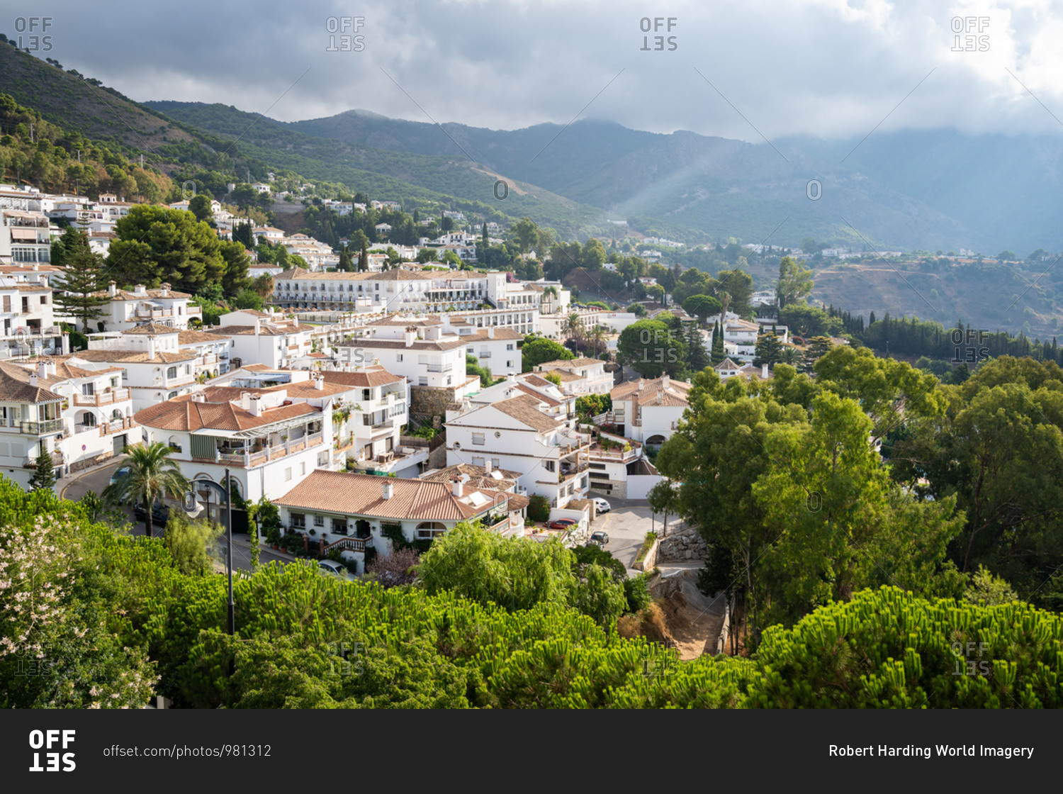 Sun rays burst through the clouds over the white washed buildings of Mijas Pueblo, Andalusia, Spain, Europe