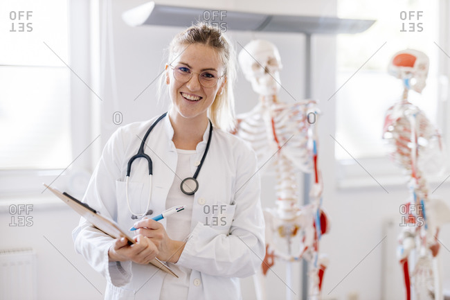 Portrait of smiling female doctor with anatomical skeleton in the background