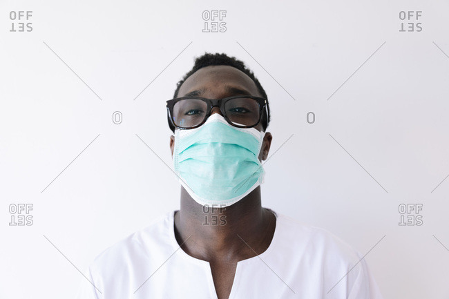 Close-up of afro doctor wearing surgical mask against white background