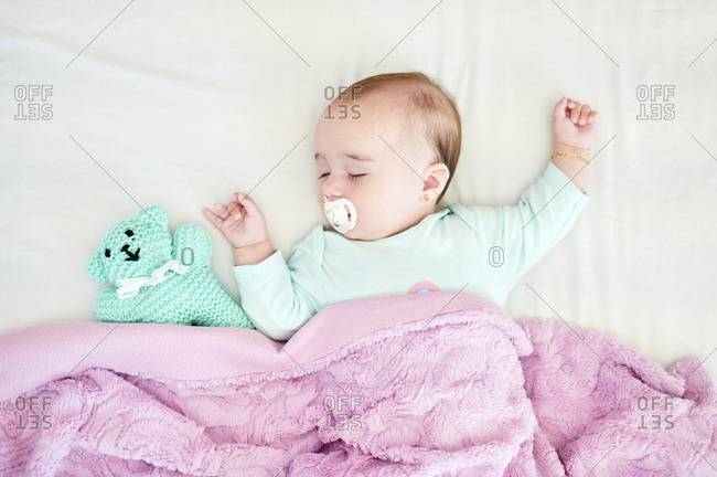 Portrait of sleeping baby girl with pacifier and cuddly toy