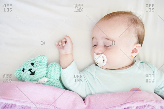 Portrait of sleeping baby girl with pacifier and cuddly toy