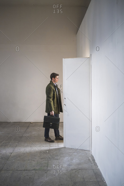 Businessman with briefcase leaving sparse room