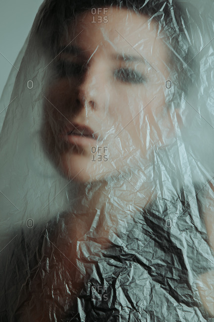 Portrait of a serious and attractive woman with short hair covered in plastic in studio looking at the camera