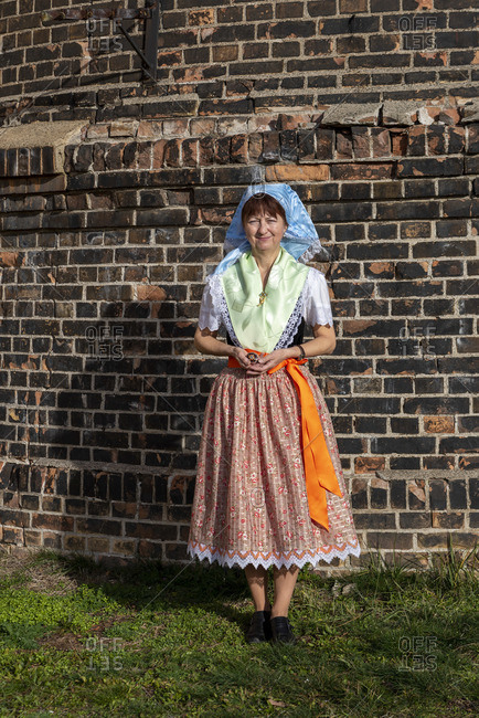 A woman wears the Sorbian costume, holding an ornamented Easter egg in her hands.