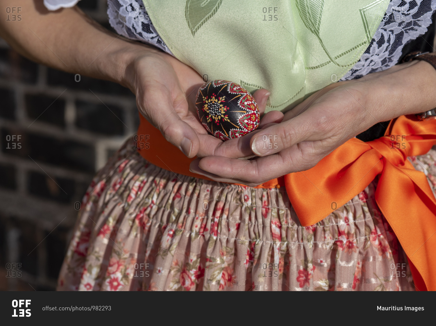 A woman wears the Sorbian costume, holding an ornamented Easter egg in her hands.
