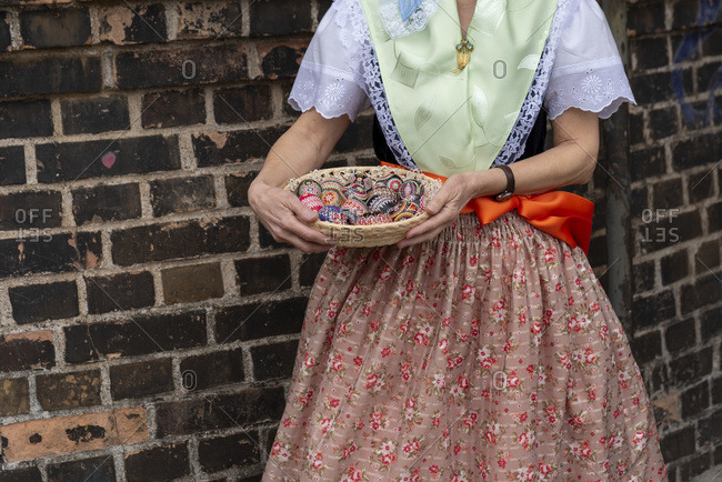A woman is wearing the Sorbian costume, holding a basket with decorated Easter eggs in her hands.