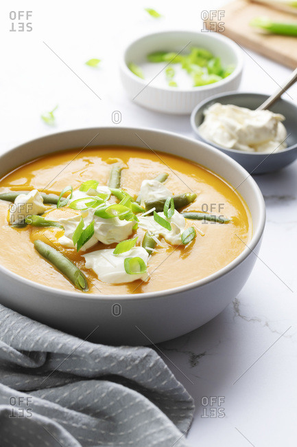 Creamy pumpkin soup and green beans with sour cream and sliced spring onions.