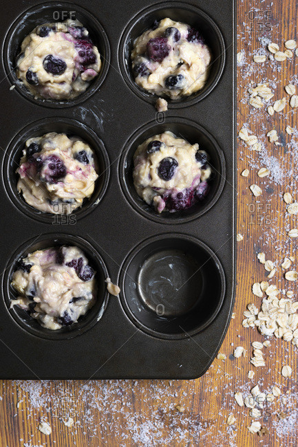 Mixed berry and oat muffin batter in a muffin pan.