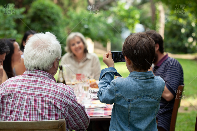 Boy photographing family at outdoor meal