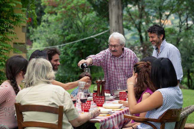 Senior man pouring wine at family meal