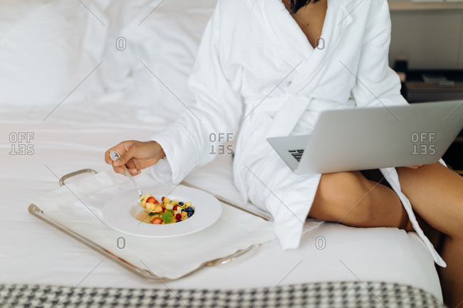 Woman using laptop and having breakfast in suite
