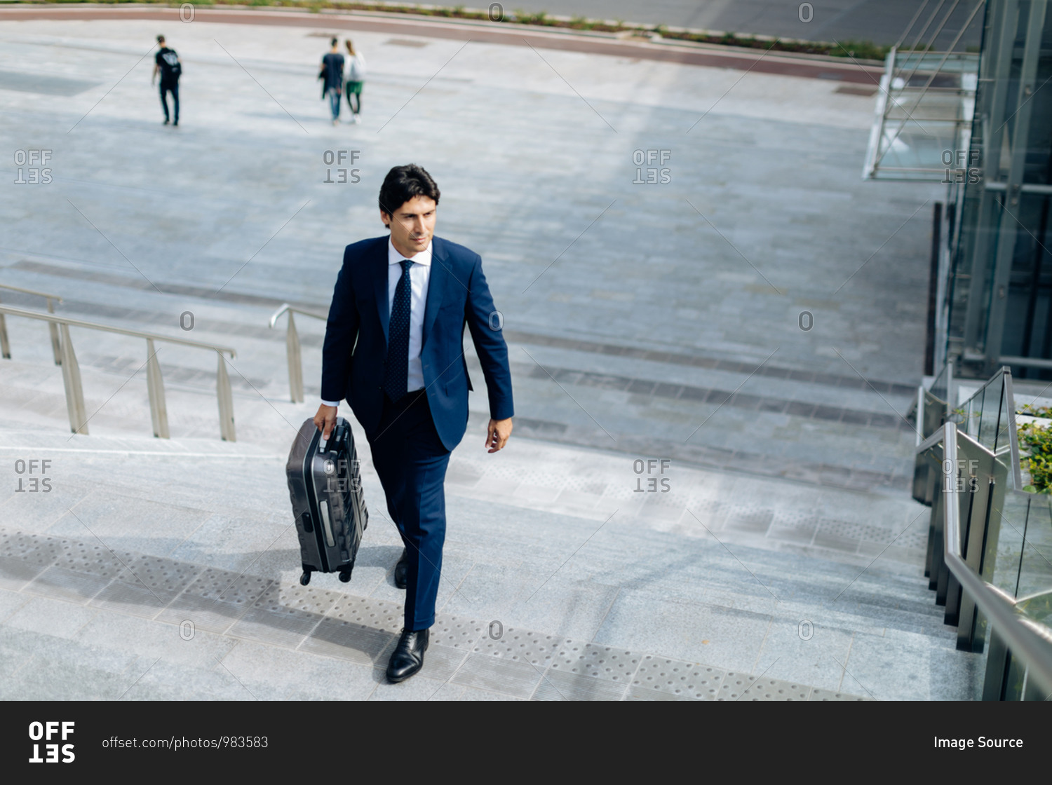 Businessman walking up stairway with carry on suitcase