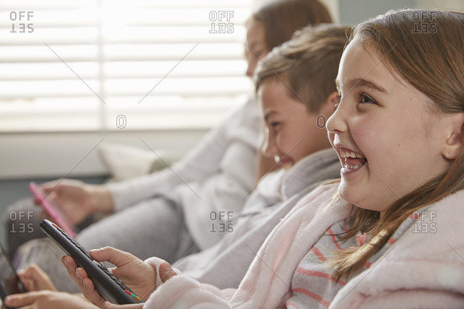 Group of children sitting on a sofa in their pajamas, watching television.