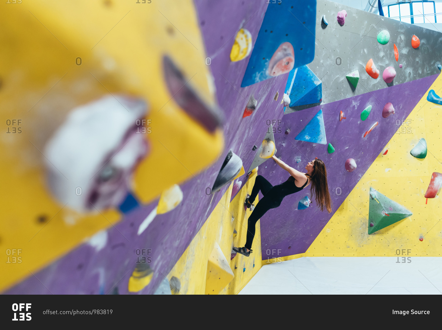 Side view of woman ascending rock climbing wall.