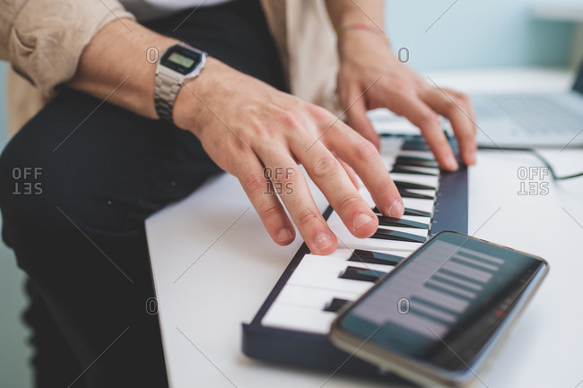 High angle close up of man playing on keyboard.