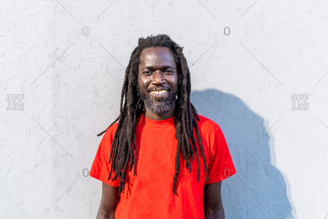 Portrait of Black man with dreadlocks wearing red T-Shirt, standing in