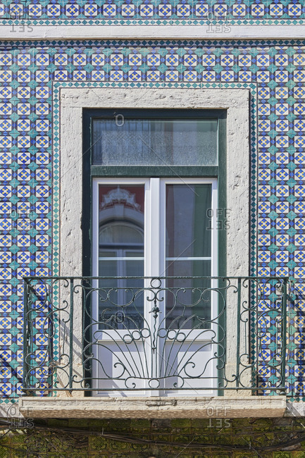 Small balcony with wrought iron railings in apartment building with Moorish tiles in Lisbon, Portugal
