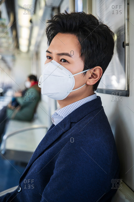 Young man wearing a mask sitting on the train